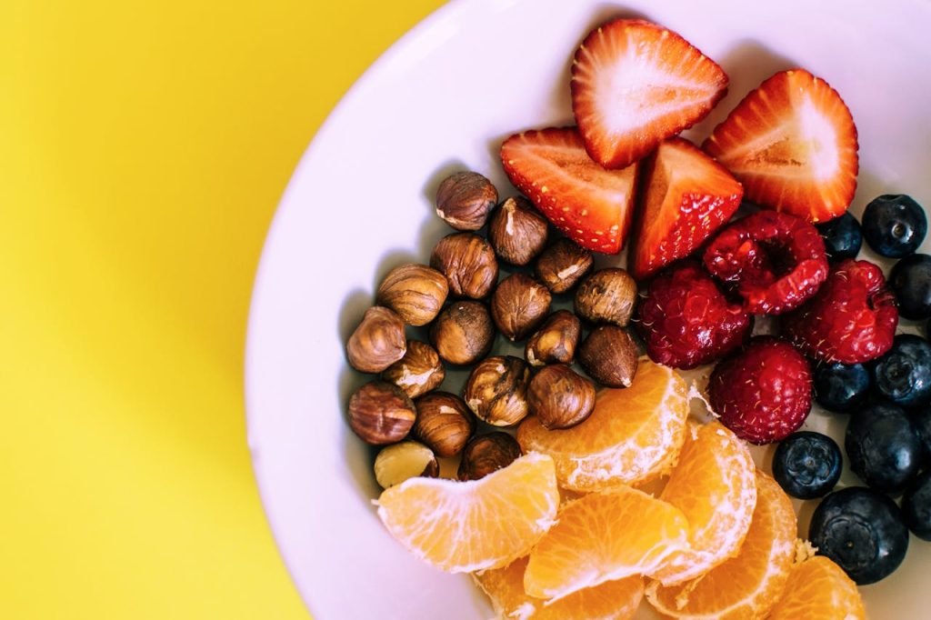 Ángel Portela. Close-up of a bowl with fresh fruits and nuts against a vibrant yellow backdrop.